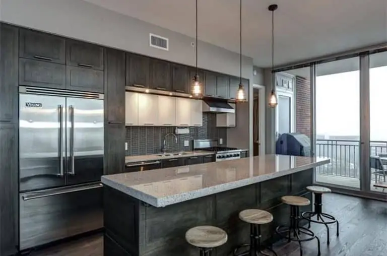 Grey kitchen with dark wood cabinets pendant lights large island